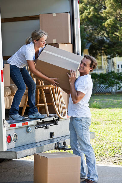 istock Young couple with moving van in driveway lifting boxes 186875716