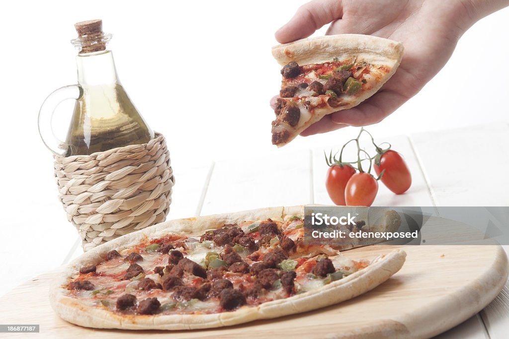 Pizza Human hand taking a slice of pizza from a whole pizza.  Cooked Stock Photo