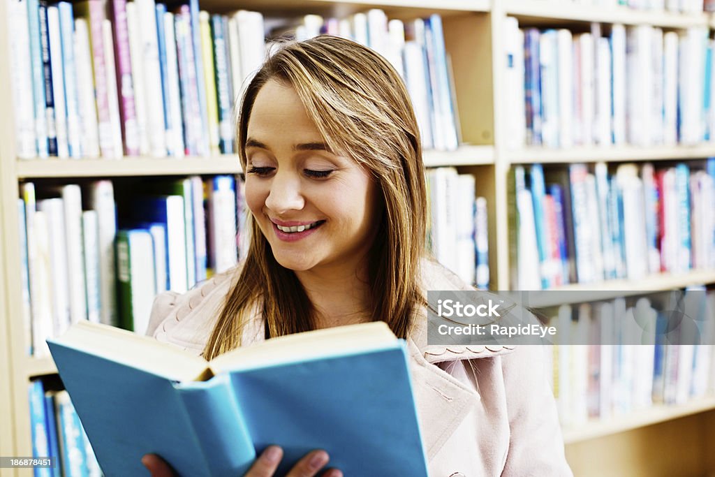 Profesor sonriente, Bibliotecario o madre de la lectura en la biblioteca - Foto de stock de 20 a 29 años libre de derechos