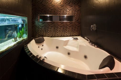 Bathroom interior with a massage bathtube and a fish tank.