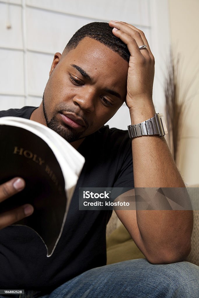 Reading the Bible Man sitting on the couch reading his Bible. Adult Stock Photo