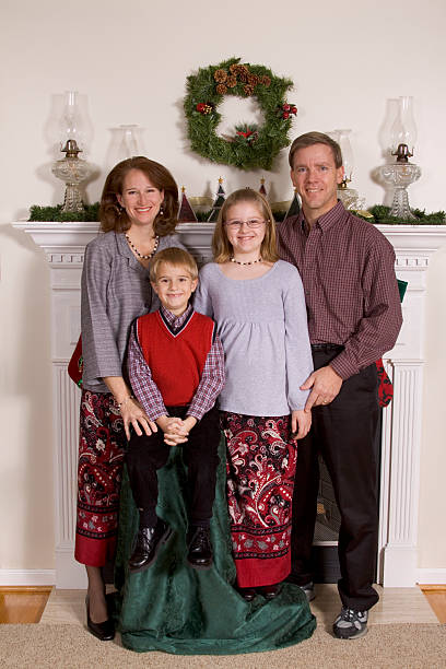 Family of Four Posing For Christmas Card Picture By Fireplace stock photo