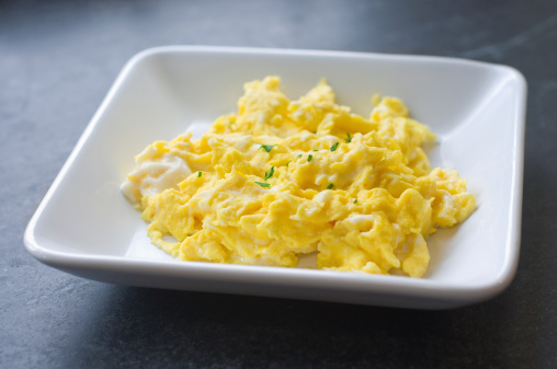 A plate of scrambled eggs sitting by a window on a soapstone countertopSimilar:
