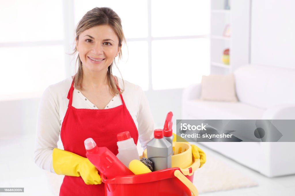 Jovem maid com bucketful olhando para a câmera. - Foto de stock de Empregrada de limpeza royalty-free