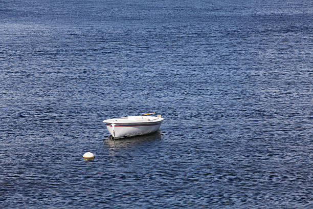 A small, well-worn dinghy used as transportation to and from shore (to board a larger boat normally tied up here) is moored to a floating buoy. 