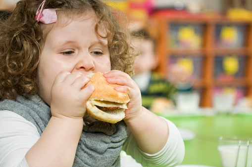 The girl is eating a hamburger.