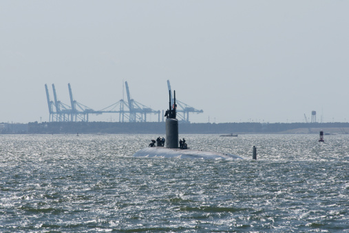 A US Navy submarine heads off to the ocean for a patrol on a hazy day