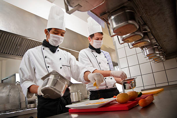 Chef and trainee work in a hotel kitchen, preparing a meal stock photo