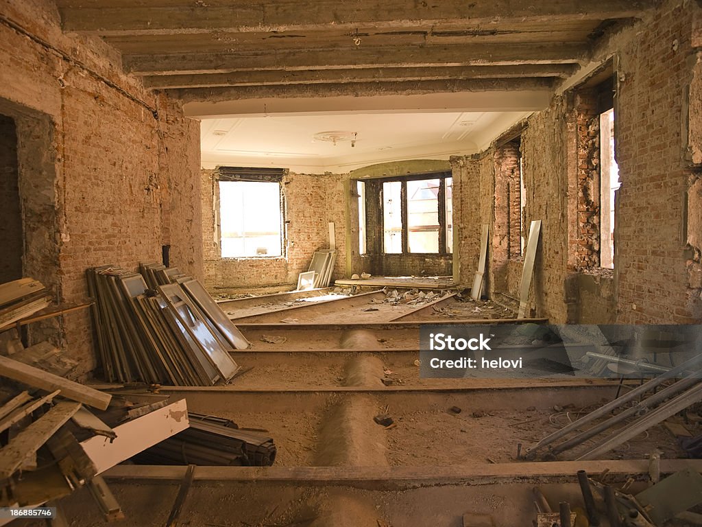 Reconstruction "Remodeling interior of home or office building. Dimly lit, light coming throe windows. Some scattered wood and broken windows on the floor." Awe Stock Photo