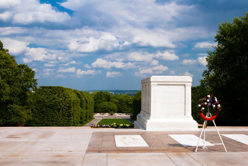 Tomb of the Unknown Soldier in Arlington Virginia with blue sky and trees behind it.