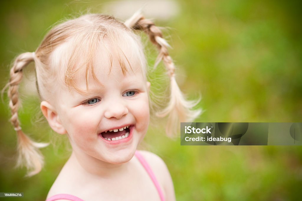 Happy Little Blonde Girl Laughing Outside Color photo of a happy little, blonde-haired girl smiling and laughing outside on a summer day. 2-3 Years Stock Photo