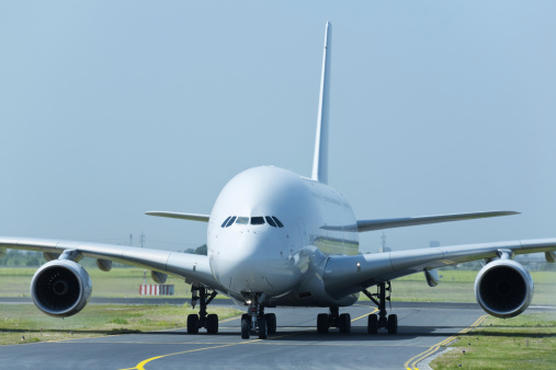 A Singapore Airlines Airbus A380-841 plane, registration 9V-SKN, taxiing after landing at Sydney Kingsford-Smith Airport as flight SQ231 from Singapore.   In the background are fuel storage tanks.  This image was taken from near Kyeemagh Beach, Botany Bay on a hot and sunny morning on 24 March 2024.