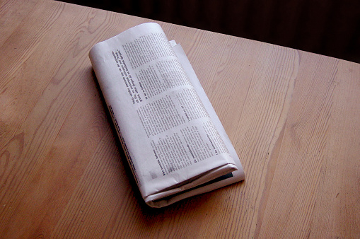folded newspaper on a wooden table.check out