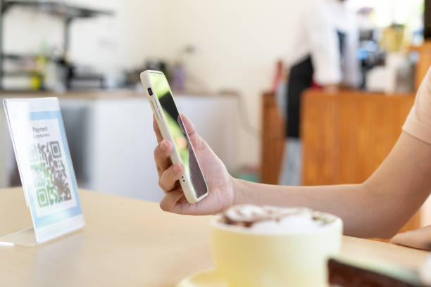 istock Woman use smartphone to scan QR code to pay in cafe restaurant with a digital payment without cash. Choose menu and order accumulate discount. E wallet, technology, pay online, credit card, bank app. 1868916034