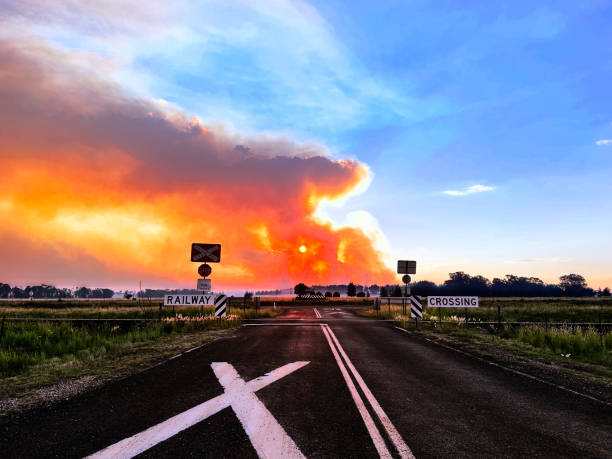 Railway crossing and orange sky due to intense bush fire smoke and sunset in rural Australia