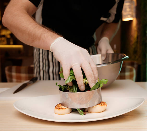 istock A chef is plating an appetizer with scallops on white plate 186907588