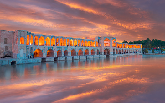People resting in the ancient Khaju Bridge at amazing sunset - Isfahan, Iran
