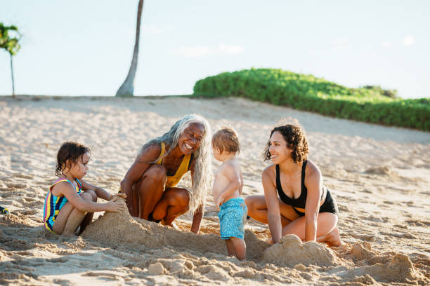 istock Multi-generation family plays in the sand at the beach 1869117362