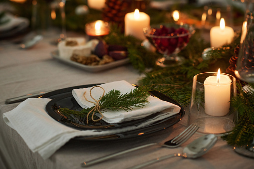 Closeup of plate with napkin decorated with fir branch displayed on festive table on christmas eve
