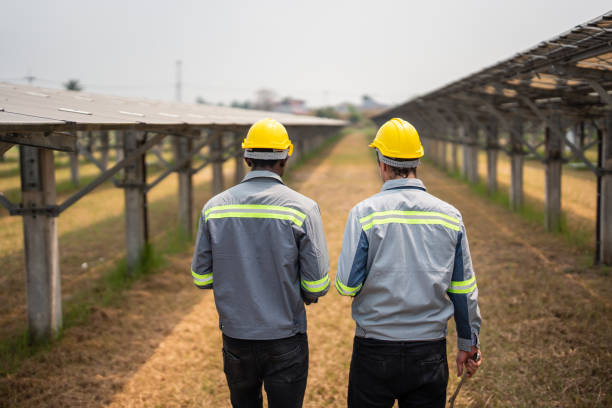 istock Professional engineer work to maintenance of photovoltaic panel system. Attractive technician worker working on roof inspect and check solar cell panels equipment box at solar cell field during sunset 1869140529