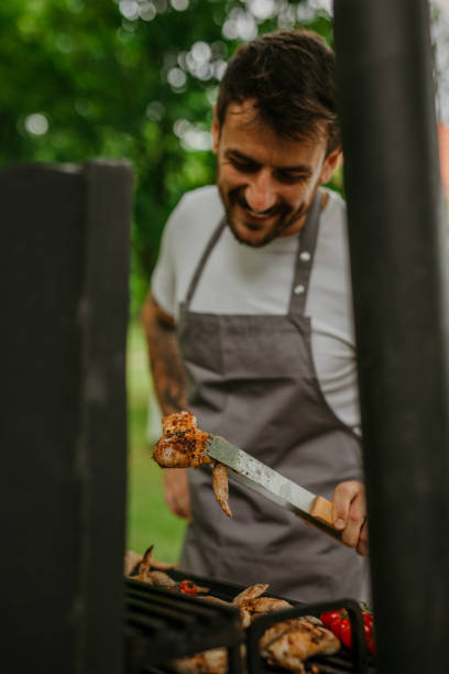 istock Happy guy enjoying a sunny day while flipping meat on his backyard grill 1869163500