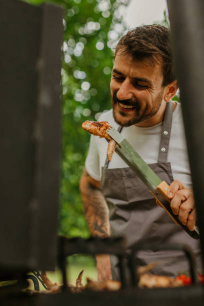 istock Happy guy enjoying a sunny day while flipping meat on his backyard grill 1869163501