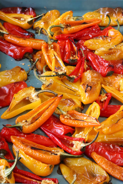 istock Full frame image of roasting tin covered with layer of cooked red, orange and yellow mini bell peppers (Capsicum annuum) with green stems, cut in half displaying pericarp (ovary wall), seeds, placenta, septum and locule (chamber), elevated view 1869168748