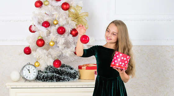 Child celebrate christmas at home. Favorite day of the year. Time to open christmas gifts. Opening christmas presents. Traditional family holiday. Kid girl near christmas tree hold gift box.