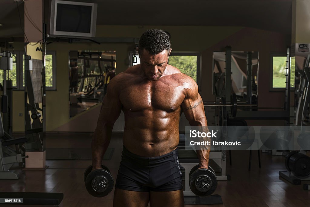 bodybuilder pesante per fare esercizio bicipiti con manubri - Foto stock royalty-free di A petto nudo