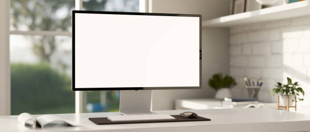istock Minimalist white workspace with a white-screen computer mockup on a white desk. 1869190284