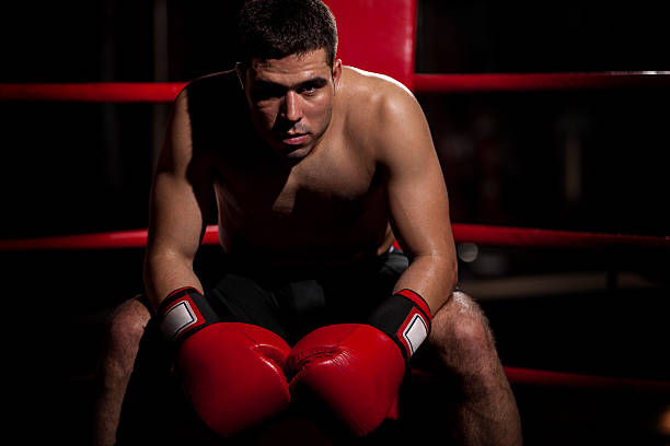Dramatic portrait of a young Hispanic boxer sitting on his corner of the ring with some copy space