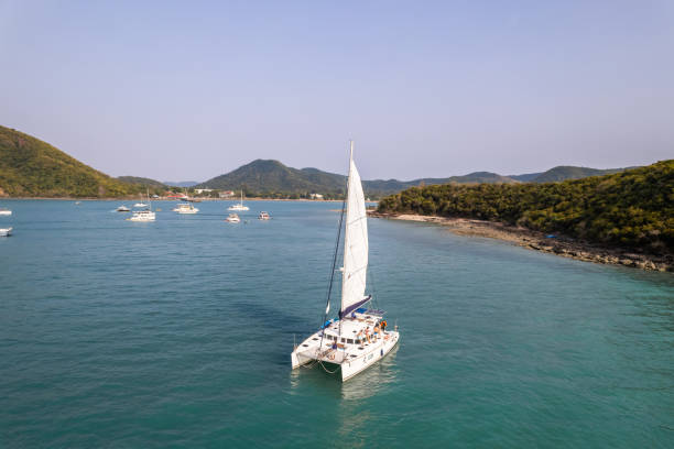 vue aérienne d’un yacht à moteur privé de luxe sur l’océan pendant l’été. de jolis jeunes hommes et femmes qui traînent, célébrant des vacances de vacances tout en naviguant en catamaran au coucher du soleil d’été. - travel locations sea mediterranean sea wind photos et images de collection