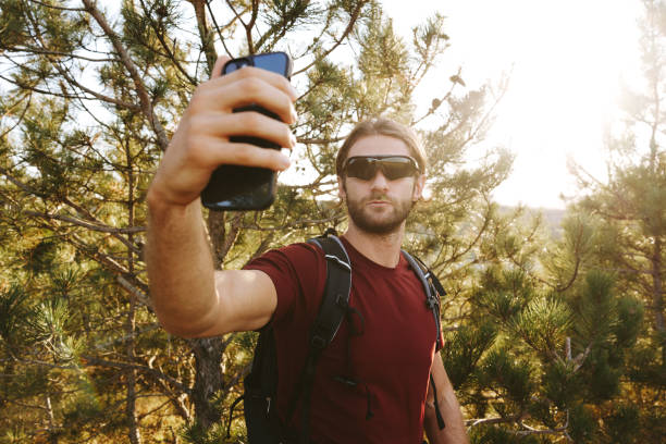istock Hiker man in sunglasses using his mobile phone in the mountain woods 1869202900