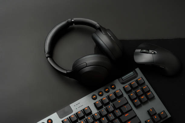 istock Headphones, computer mouse and keyboard on black background 1869208136