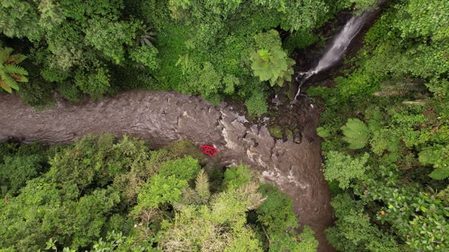 Rafting boat pass bend of small river, scenic jungles and waterfall, aerial shot