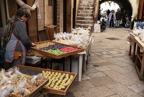 Bari, Italy - 27 November, 2023: woman pasta maker laying out her wares in the iconic Strada del Orecchiette in the old town of Bari Vecchio