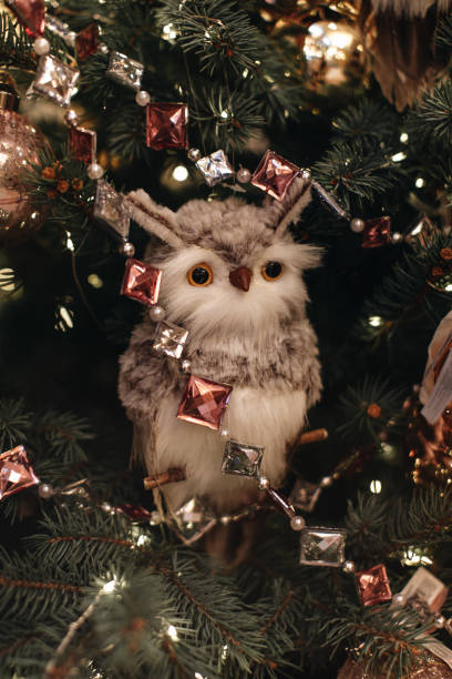 White soft toy owl figurine hanging on a Christmas tree branches with crystal beads