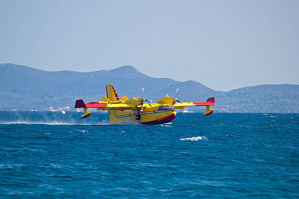 Firefighting airplane (airtanker, water bomber) flying over sea and taking water