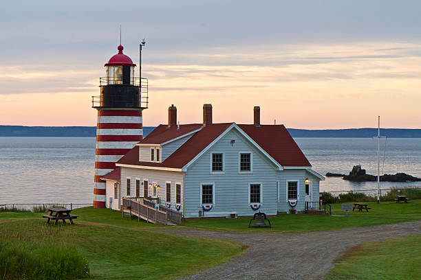 First Light on West Quoddy Head Lighthouse Firsat morning sunshine on West Quoddy Head Lighthouse, the Easternmost point in the United States, in Quoddy Head State park, Maine. quoddy head state park stock pictures, royalty-free photos & images