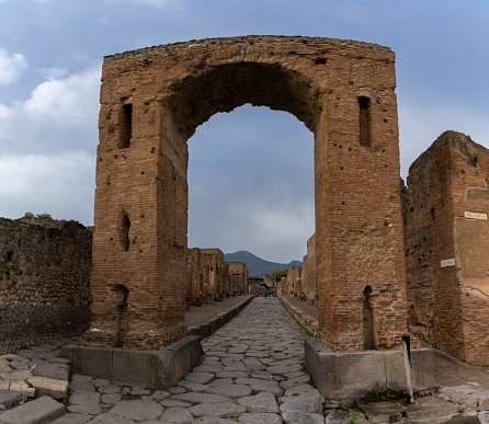 Pompei, Italy - 25 November, 2023: stone arch and long street in the ancient city of Pompeii
