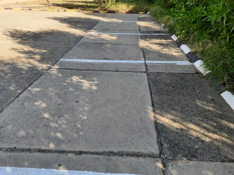 A parking space next to a black and white sidewalk and trees