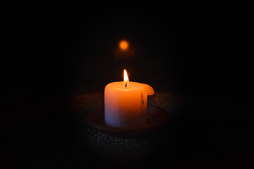 A burning candle.Bright light on dark background.RIP darkness template. lighting a candle in the darkness.Copy space.