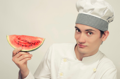 Portrait of a beautiful chef and a slice of a green melon