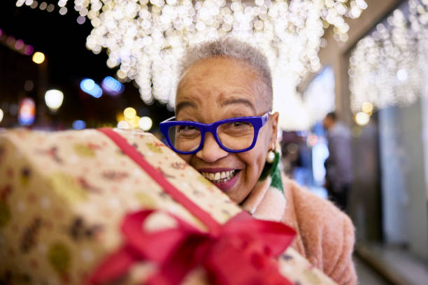 istock Cheerful Senior Woman Giving a Present  to Camera 1869344764