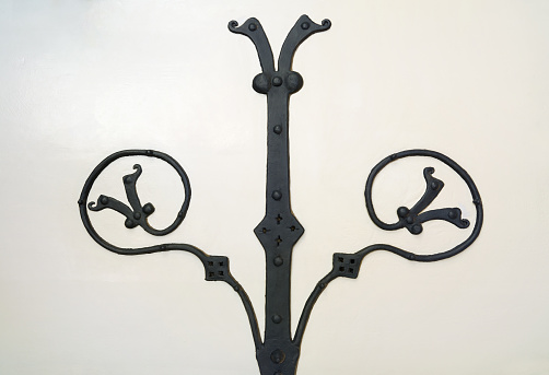 Old artful wrought iron hinge on a light painted wall