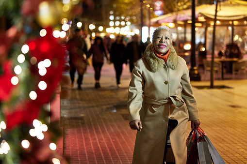 Senior woman walking in the street doing Christmas shopping.