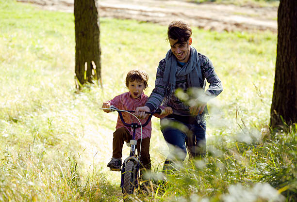 istock father learning his son to ride on bicycle 186941496