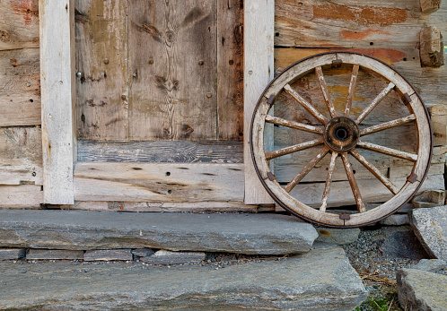 A wooden wheel leaning against a wall with a door