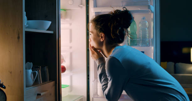 woman looking in her fridge - esfomeado imagens e fotografias de stock
