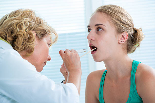 Medical exam Doctor checking with depressor sore throat to teenage girl lymph node photos stock pictures, royalty-free photos & images